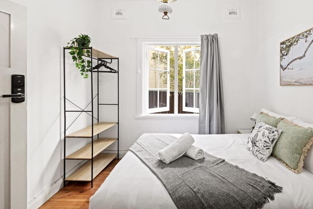 a white bedroom with a bed and a book shelf at Double Room In Maroubra in Sydney