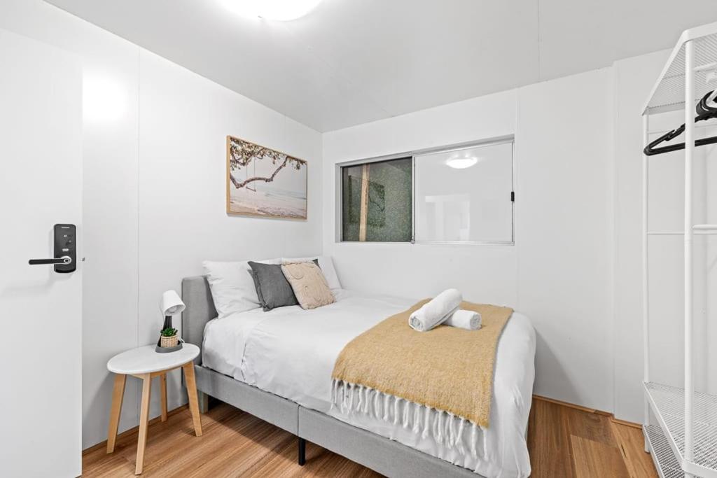 a white bedroom with a bed and a table at Private Grannyflat Room In Maroubra in Sydney