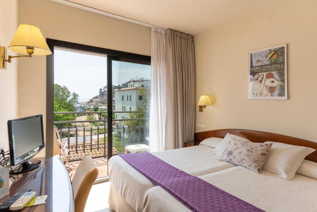 um quarto de hotel com uma cama e uma varanda em RVHotels Avenida em Tossa de Mar