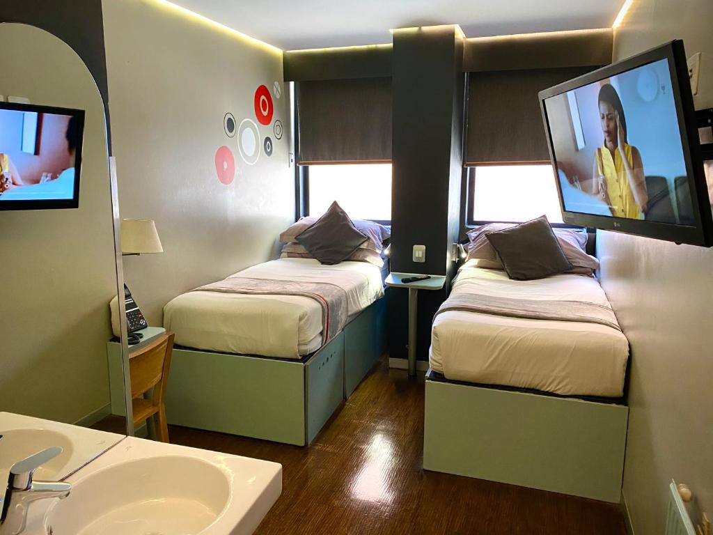 baño con 2 camas, lavamanos y TV en Bannister Hotel, en Johannesburgo