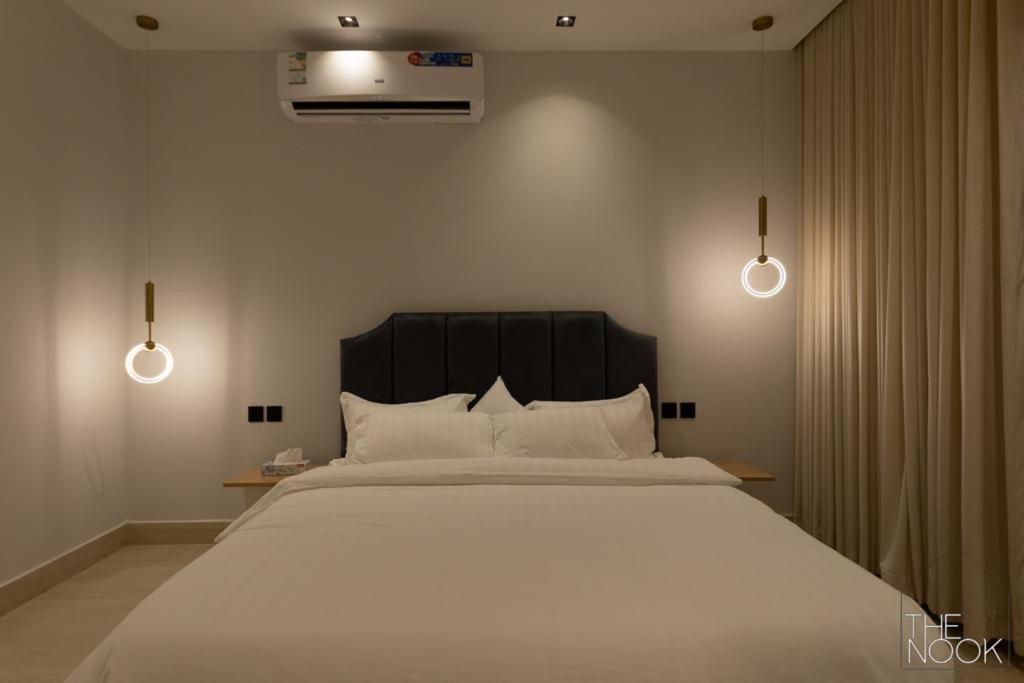 1 dormitorio con 1 cama blanca grande y 2 luces en شقة فخمة 3 غرف نوم في حي الملقا قريبه من البوليفارد The Nook, luxury 3BD Flat in malqa district near BLVD, en Riad