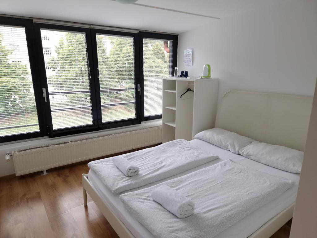 um quarto com 2 camas brancas e janelas grandes em Most Hostel em Ljubljana