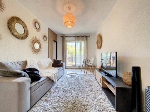 un salon avec un canapé et une télévision dans l'établissement 2 pièces proche plage + parking, au Golfe-Juan