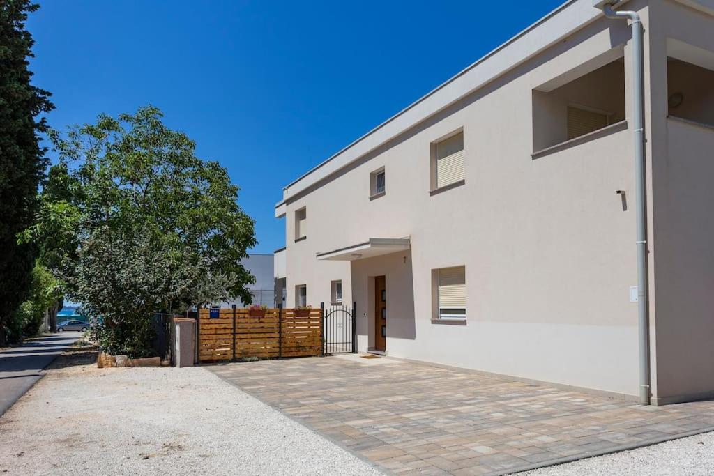 a white building with a fence and a tree at Modern holiday house near beach in Fažana