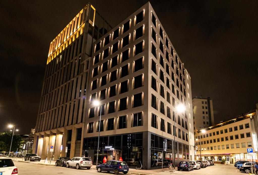 a tall building with cars parked in a parking lot at Smart Hotel Central in Milan