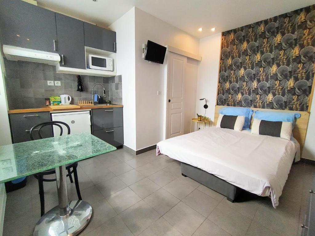 Cet appartement comprend une chambre avec un lit et une table ainsi qu'une cuisine. dans l'établissement Appart-Hôtel Le Djurdjura Suresnes-Nanterre-La defense, à Nanterre