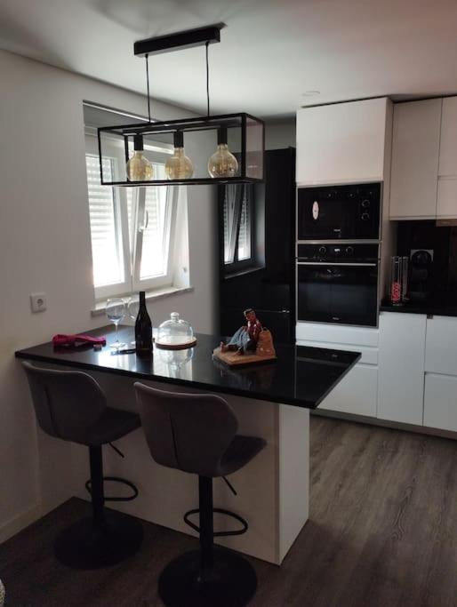 a kitchen with a black counter and two bar stools at Katyto house in Costa da Caparica