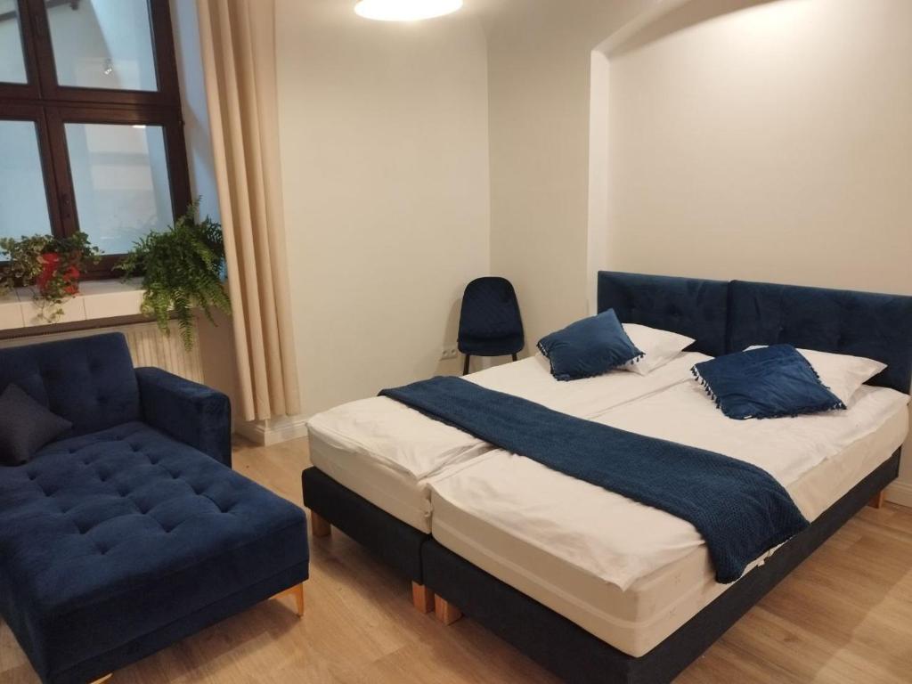 a bedroom with a bed and a blue couch at Urban Nest Apartments Szewska 21-R in Krakow