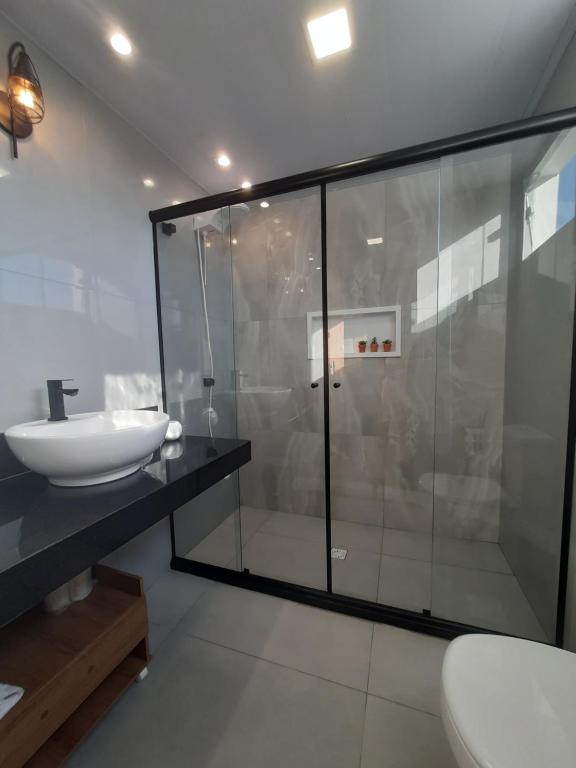 uma casa de banho com uma cabina de duche em vidro e um lavatório. em Jardim Tropical em Lauro de Freitas