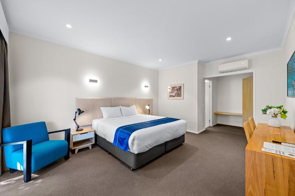 a hotel room with a bed and a blue chair at Rowville International Hotel in Rowville