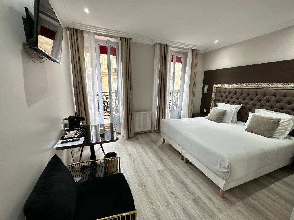 a bedroom with a large white bed and a television at Hotel Riviera Renovated in Paris