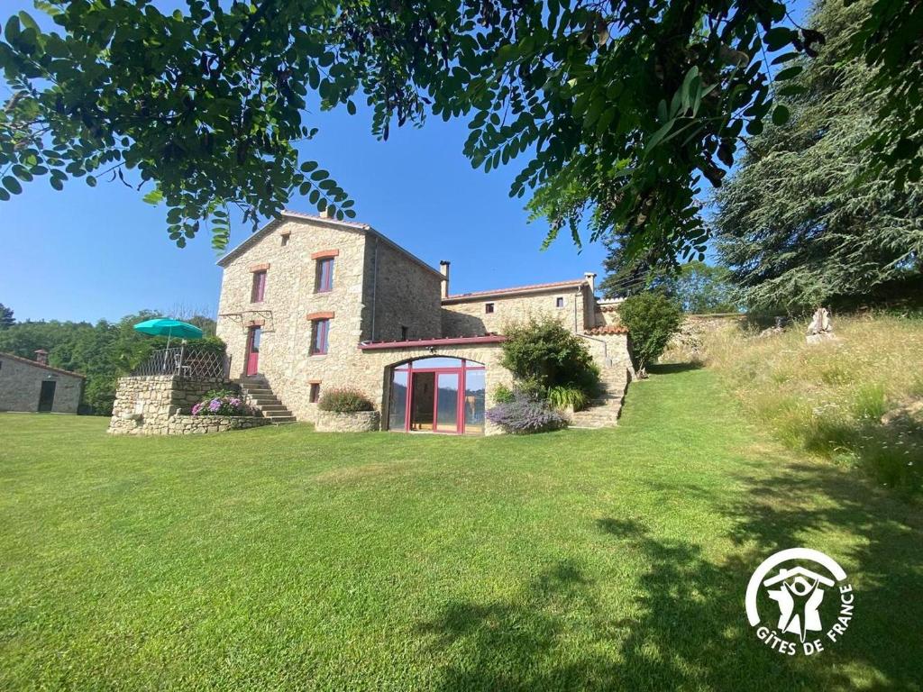 una casa su una collina con un prato di MAS LO BOACH a Saint-Laurent-de-Cerdans