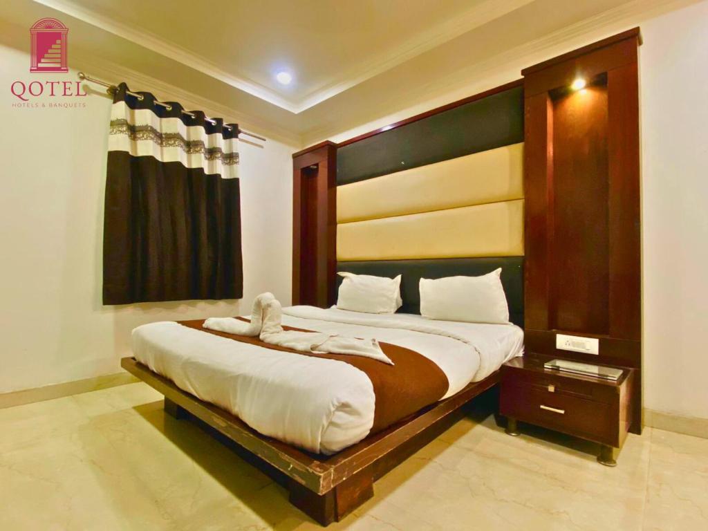 a bedroom with a large bed with a wooden headboard at Qotel Hotel Pitampura Couple Friendly in New Delhi