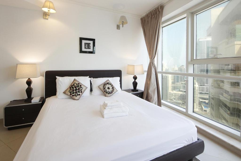 a bedroom with a white bed with a large window at SHH - Furnished 1BR Apartment in Goldcrest Executive, Jumeirah Lake Towers in Dubai