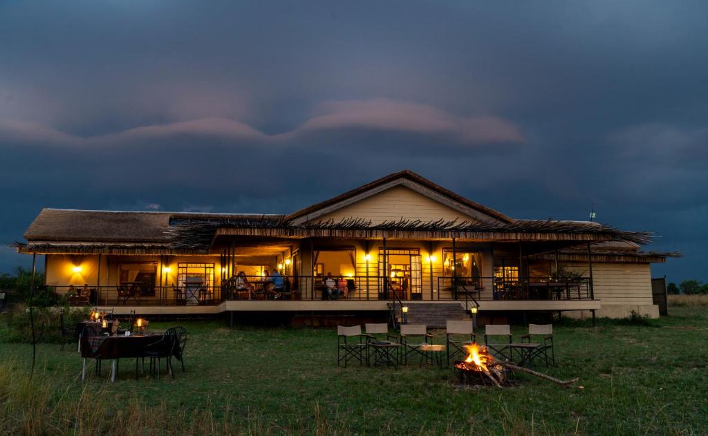 a house with a fire in front of it at night at Serengeti River Camp in Robanda