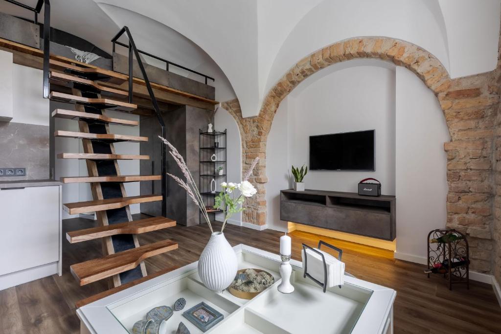 a kitchen and living room with a spiral staircase and a table at Cozy Carmelite apartment in Vilnius
