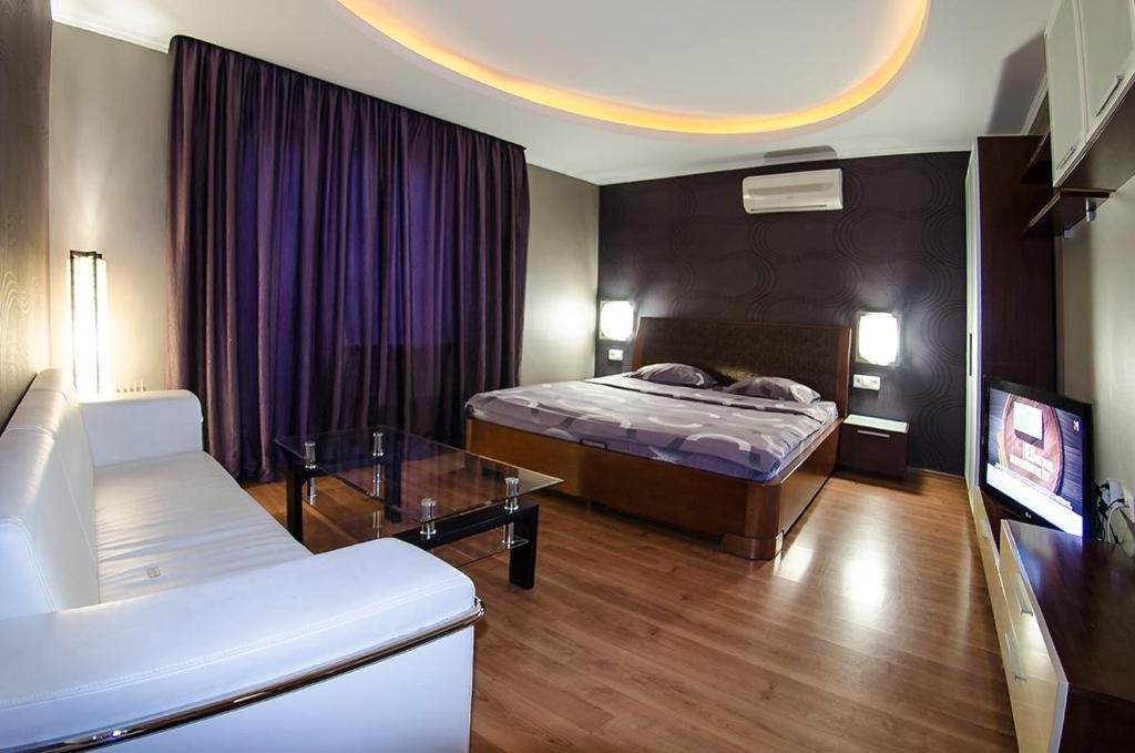 ein Hotelzimmer mit einem Bett und einem Sofa in der Unterkunft Бульвар Леси Украинки 16 джакузи люкс центр in Kiew