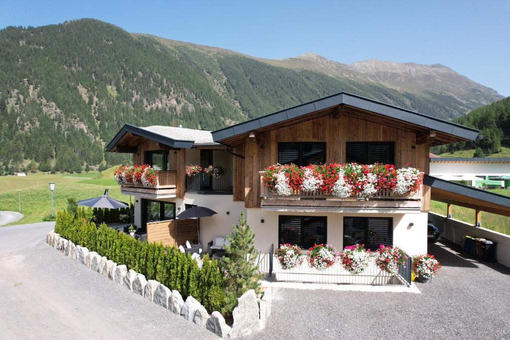 a building with flower boxes on it with mountains in the background at Alp Apart Niederthai in Umhausen