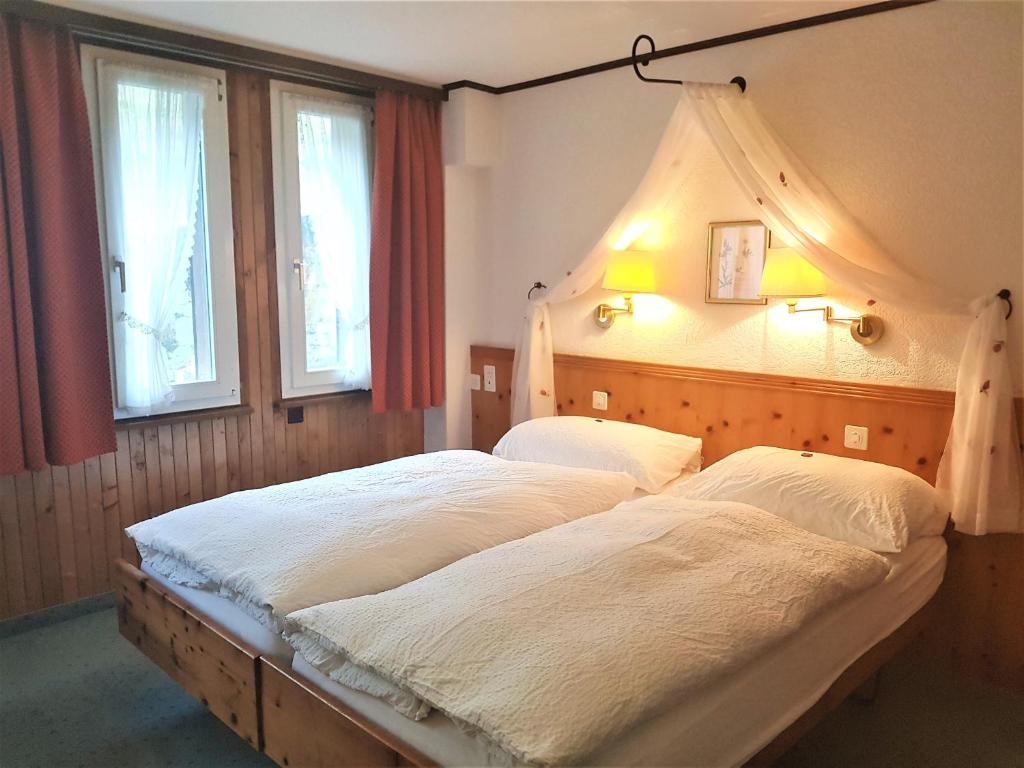 two beds in a bedroom with two windows at Self-Service Guesthouse Berggeist in Saas-Fee