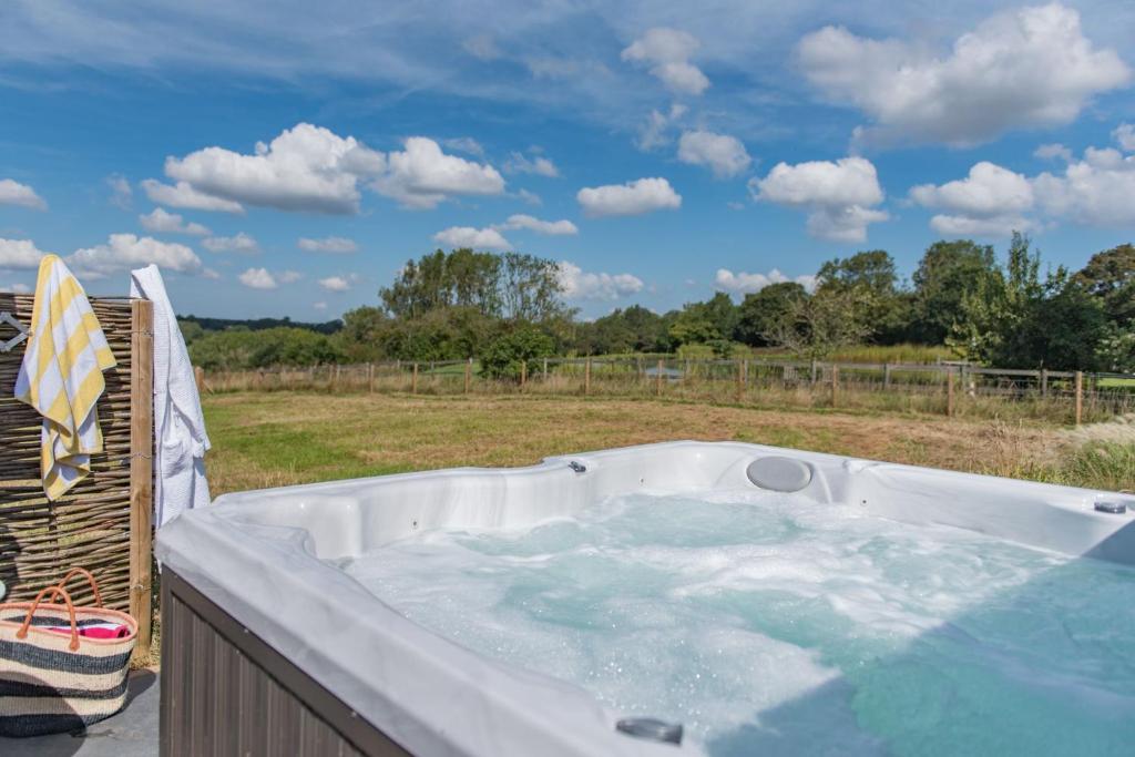 a hot tub on a deck with a view of a field at The Hayloft by Bloom Stays in Canterbury