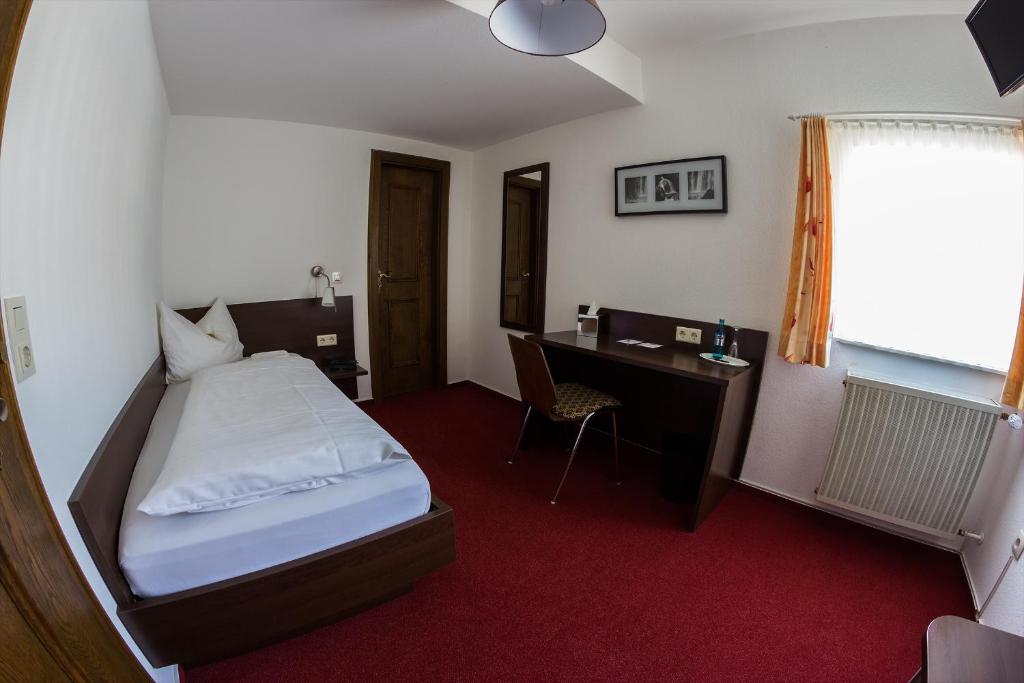a hotel room with a bed and a desk at Ratskeller Niederurff - Hotel &amp; Restaurant in Bad Zwesten