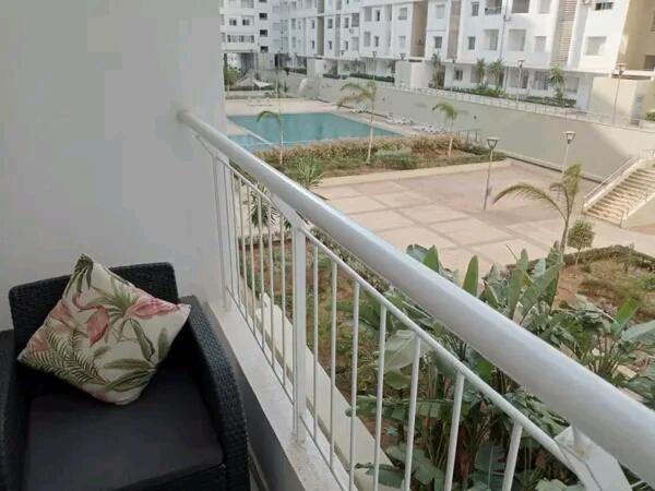 un balcon avec un banc et une piscine dans l'établissement Appartement meublé, à Agadir