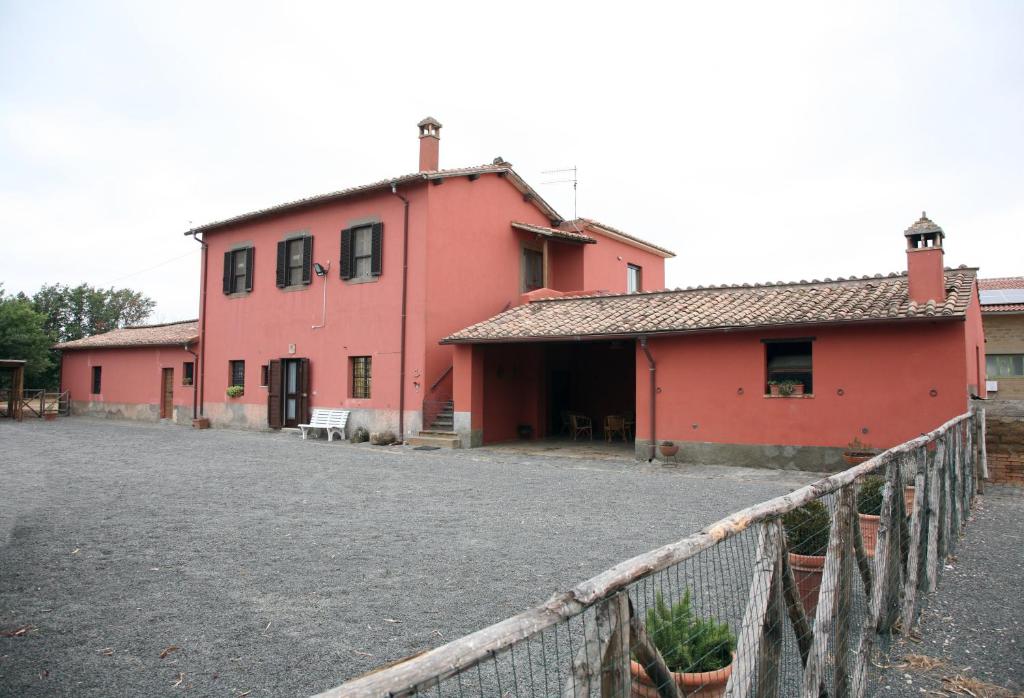 una casa rosa con una valla delante en Agriturismo Casalino dei Francesi, en Montalto di Castro