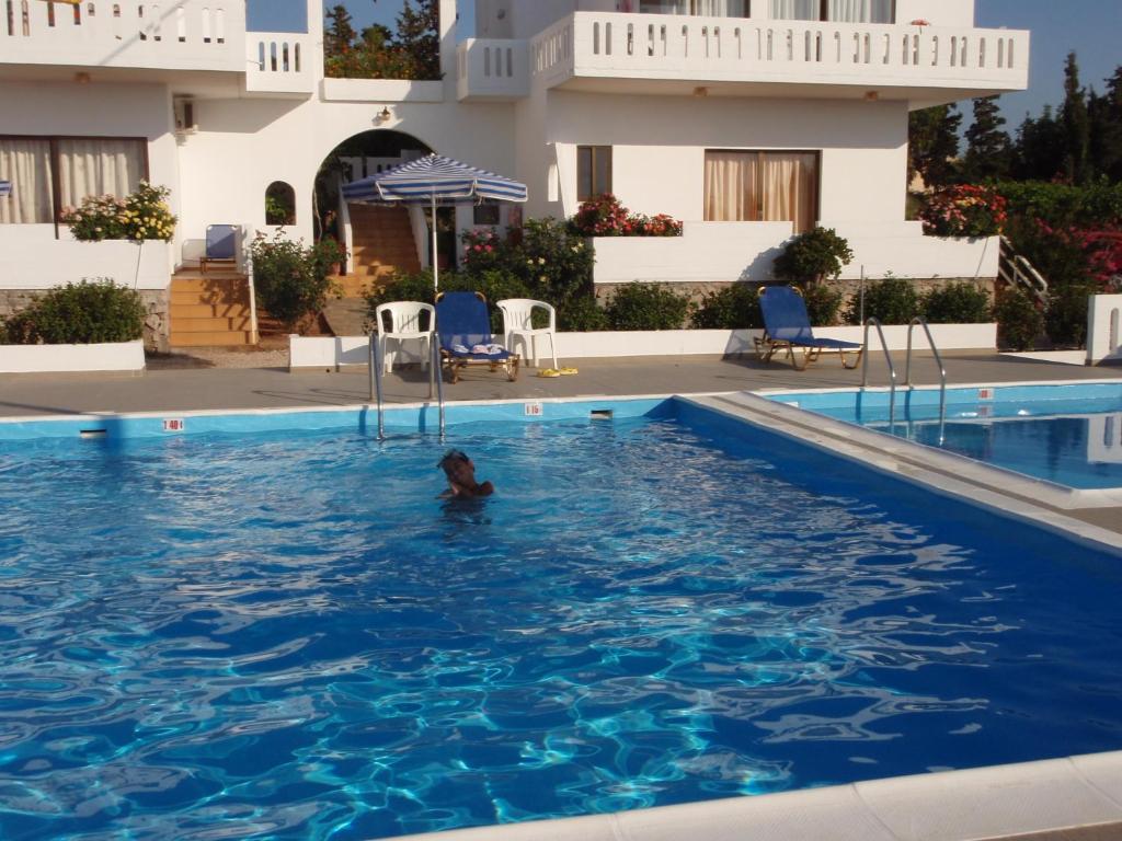 a person in the swimming pool of a hotel at Villas Michalis in Chorafakia