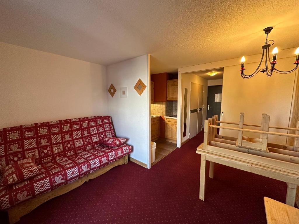 ein Wohnzimmer mit einem roten Sofa und einem Tisch in der Unterkunft Appartement les 2 alpes 1800 départ /retour skis aux pieds in Les Deux Alpes