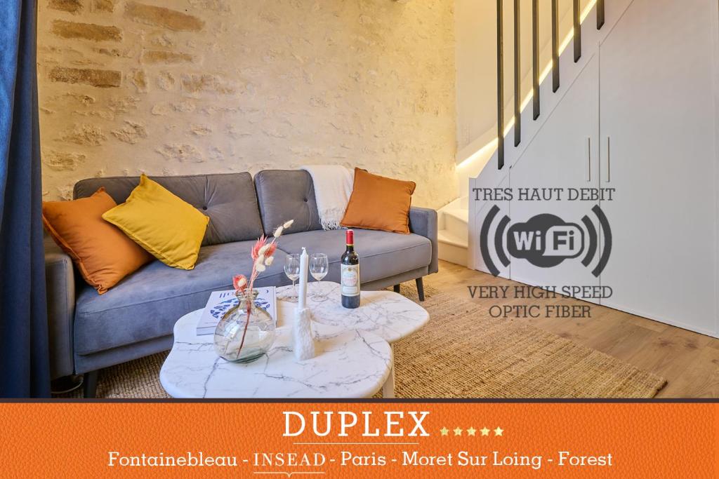 sala de estar con sofá y mesa con botellas de vino en Duplex standing 7min➤Fontainebleau-INSEAD⎮45min➤Paris en Veneux-les-Sablons