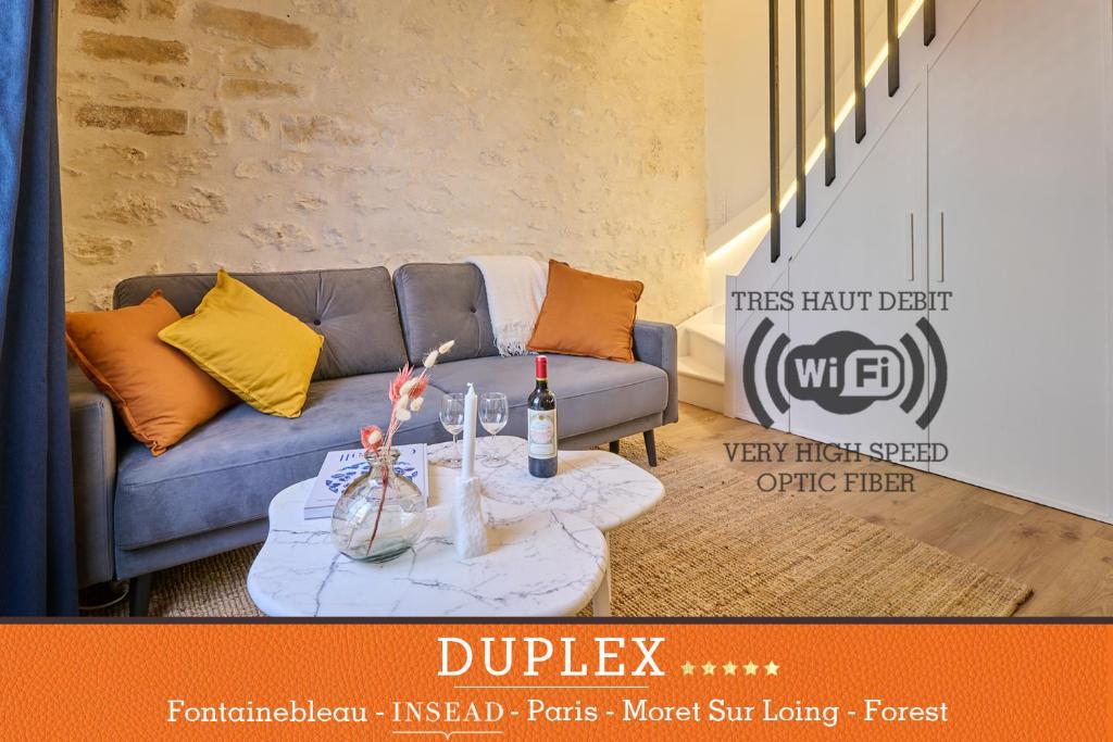 a living room with a couch and a table with wine bottles at Duplex standing 7min➤Fontainebleau-INSEAD⎮45min➤Paris in Veneux-les-Sablons