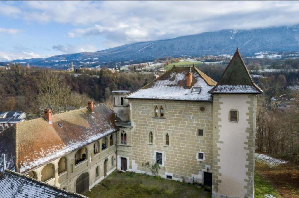 una vista aérea de un edificio antiguo con montañas en el fondo en Château De Montpon - Grand logement, en Saint-Sylvestre