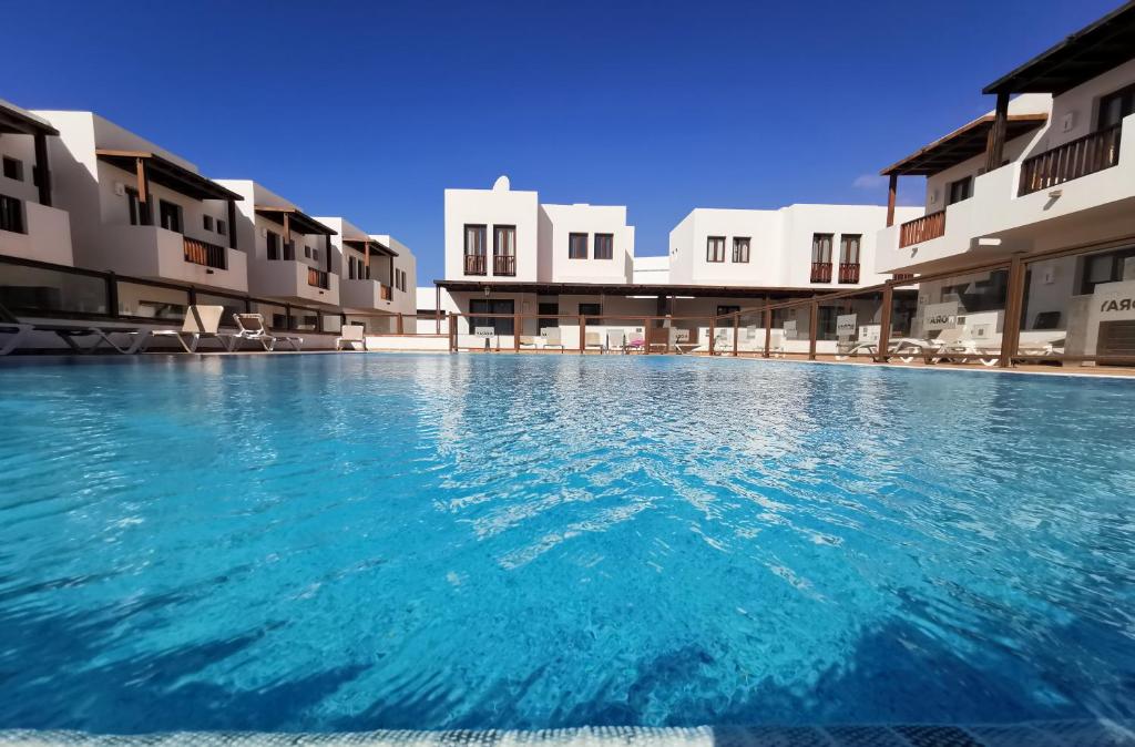 a swimming pool with blue water in front of buildings at Casa Milan in Puerto Calero