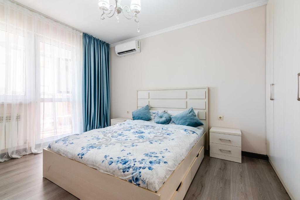 1 dormitorio con 1 cama grande con almohadas azules en ЖК Теремки en Almaty