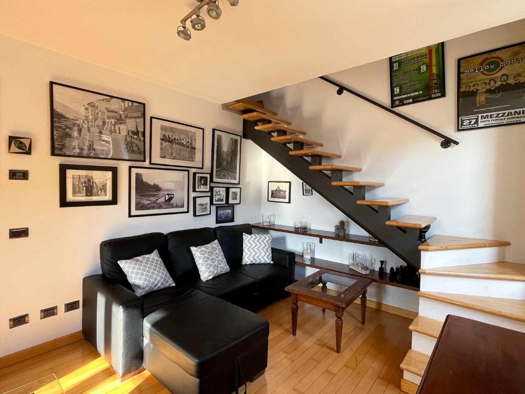 a living room with a black couch and stairs at Plinio center town apartment in Bellagio