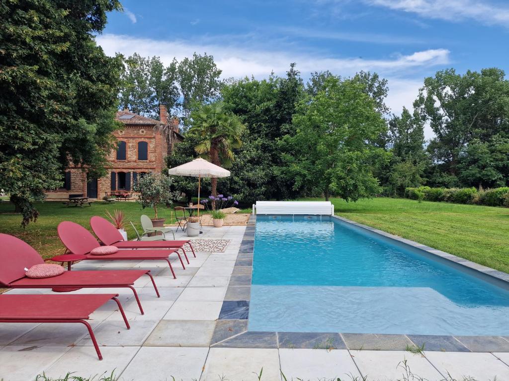 uma piscina com cadeiras e um guarda-sol ao lado de uma casa em Chambre de charme dans maison de maître em Montauban