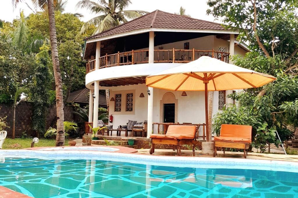 uma casa com um guarda-chuva ao lado de uma piscina em Manuastro Breeze Villa - Diani Beach em Galu