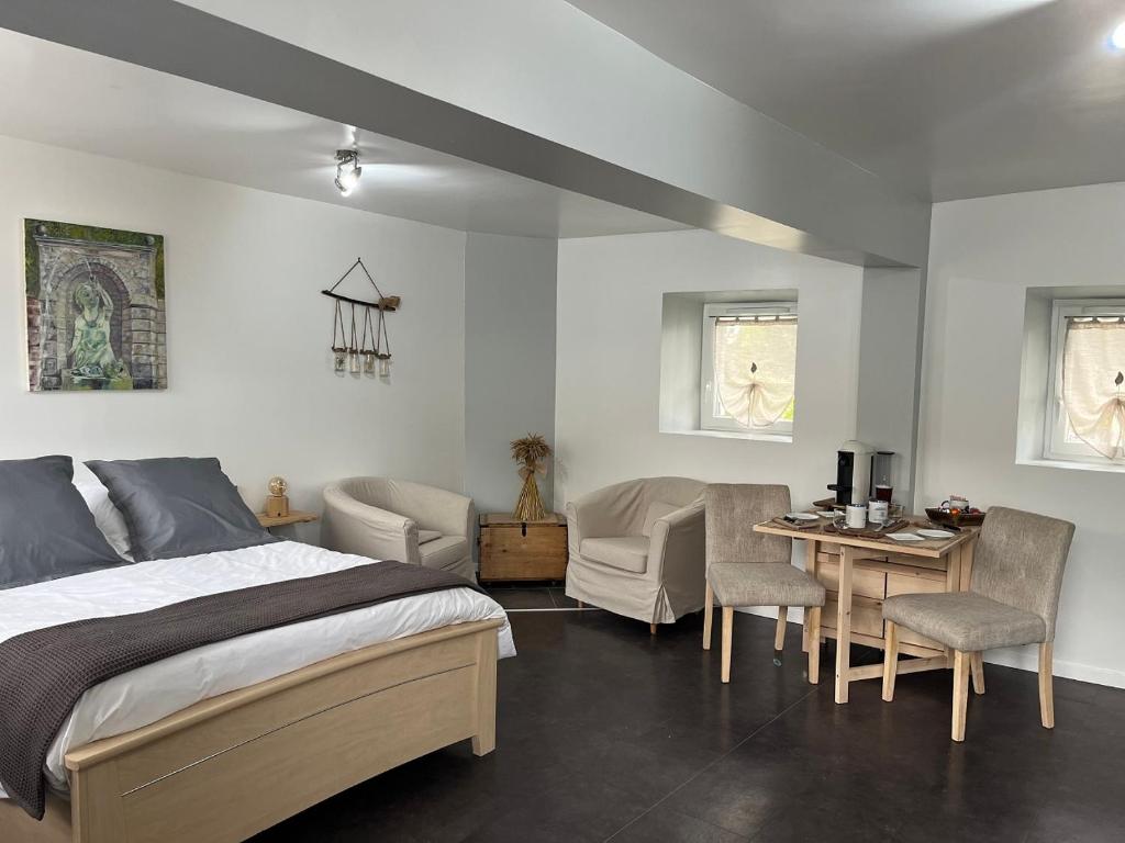 une chambre avec un lit, une table et des chaises dans l'établissement Les Jardins d'Eva et Gotham, à Civières