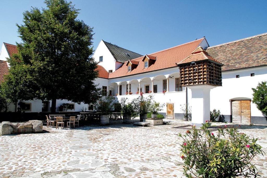 Oslip的住宿－Csello Mühle，一座白色的大建筑,有树和庭院