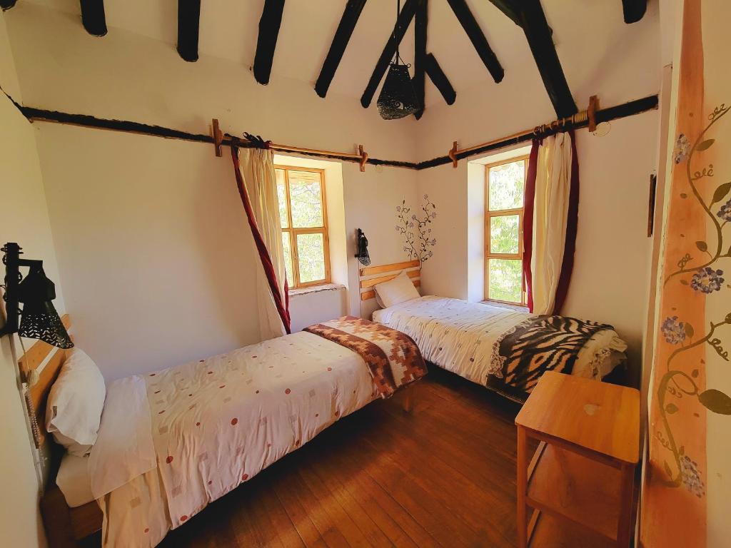 two beds in a room with two windows at Logde Casa de campo & Retreat Center in Urubamba