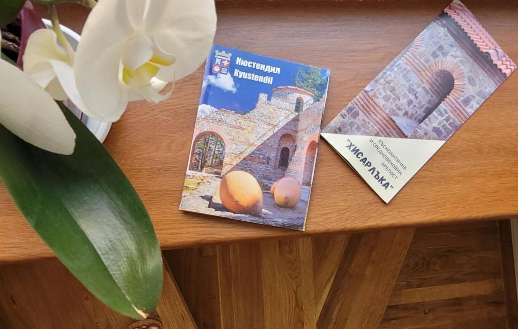 a table with two books and a vase with a flower at The House - Central Boutique Apartments in Kyustendil