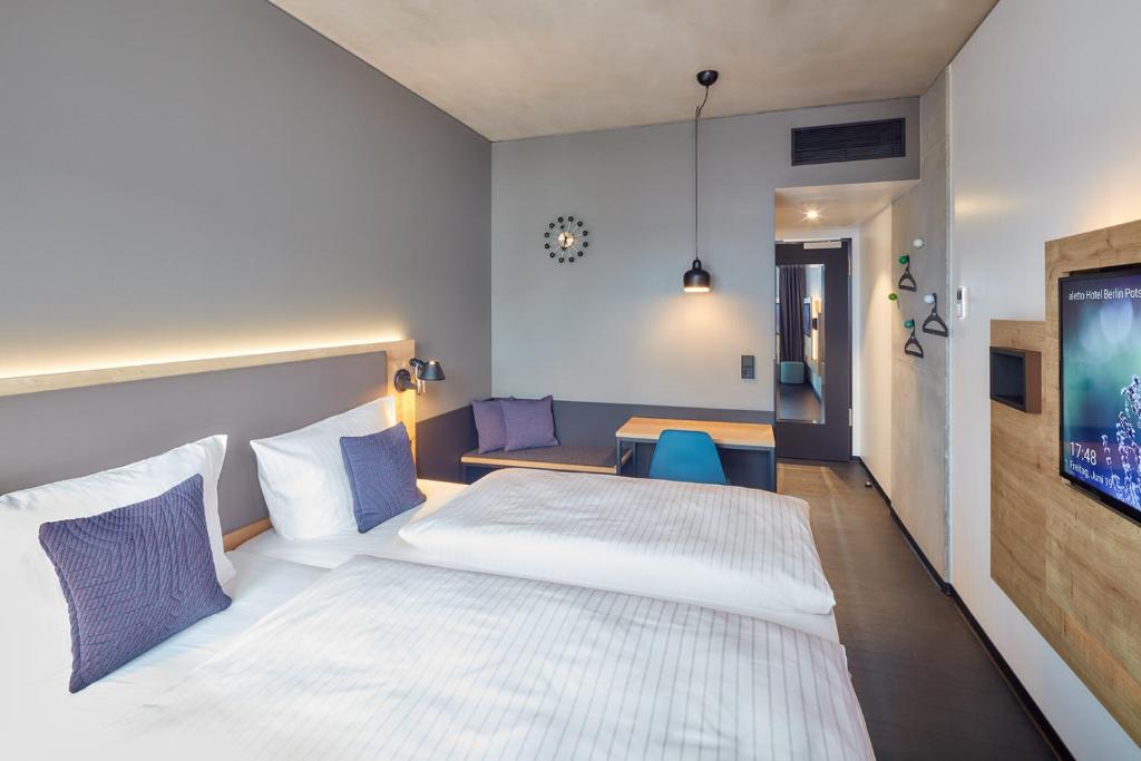 ein Schlafzimmer mit einem weißen Bett und einem Tisch in der Unterkunft aletto Hotel Potsdamer Platz in Berlin