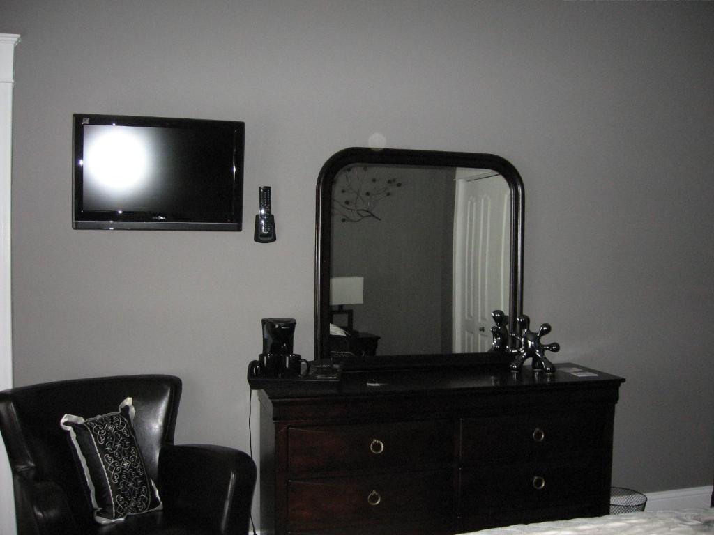 a bedroom with a dresser and a mirror and a dresser with a dress at Driftwood Heights B&B in Summerside