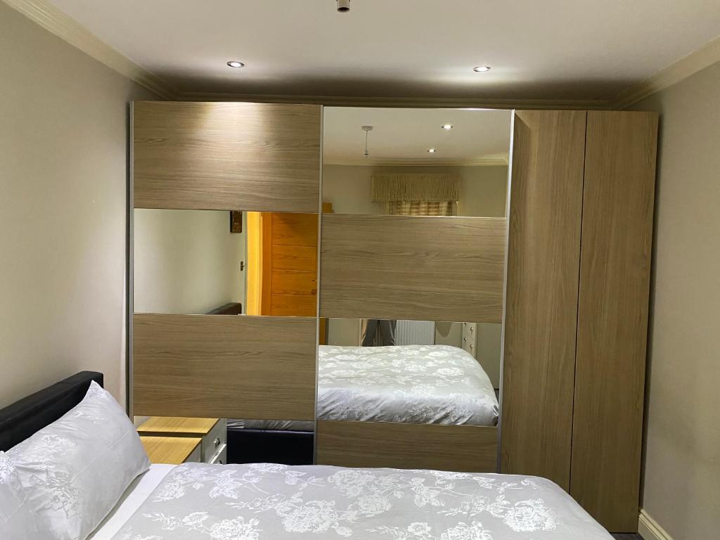 a bedroom with a bed and a large wooden closet at Ruislip Guest House in Ruislip