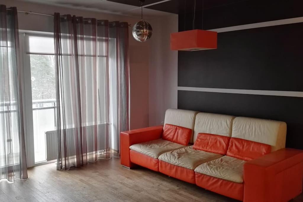 a living room with a red couch in front of a window at Wonderful apartment for Families and more in Rīga