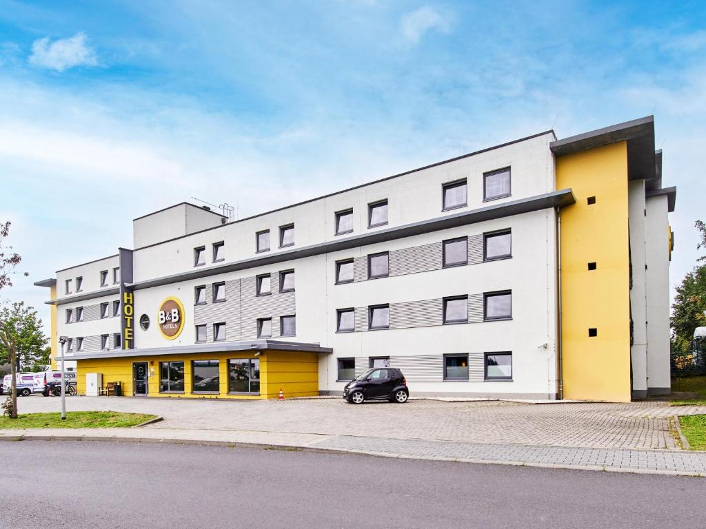 un bâtiment avec une voiture garée devant lui dans l'établissement B&B Hotel Frankfurt-Nord, à Francfort-sur-le-Main