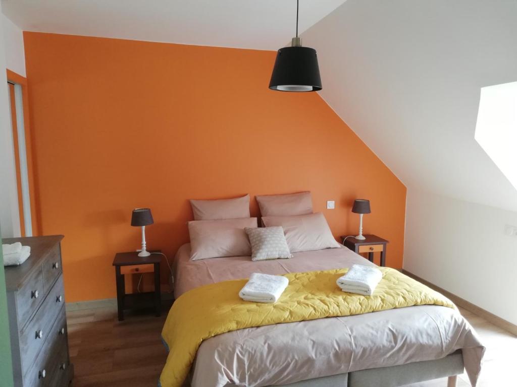 um quarto com uma cama com uma parede laranja em Chambres d'Hôtes des Hirondelles em Beaussais sur Mer