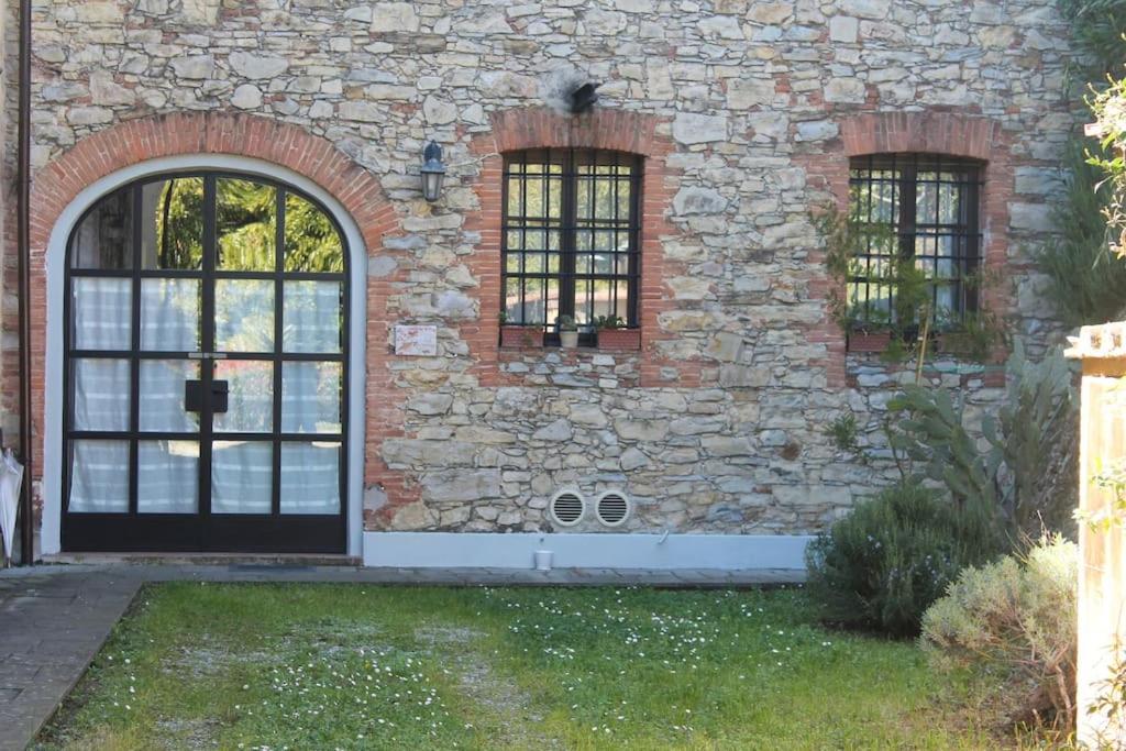 a stone building with a black door and two windows at Il Guscio in Corsanico-Bargecchia