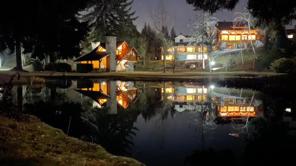 una casa di notte con un riflesso nell'acqua di Ruca Kuyen Golf & Resort a Villa La Angostura