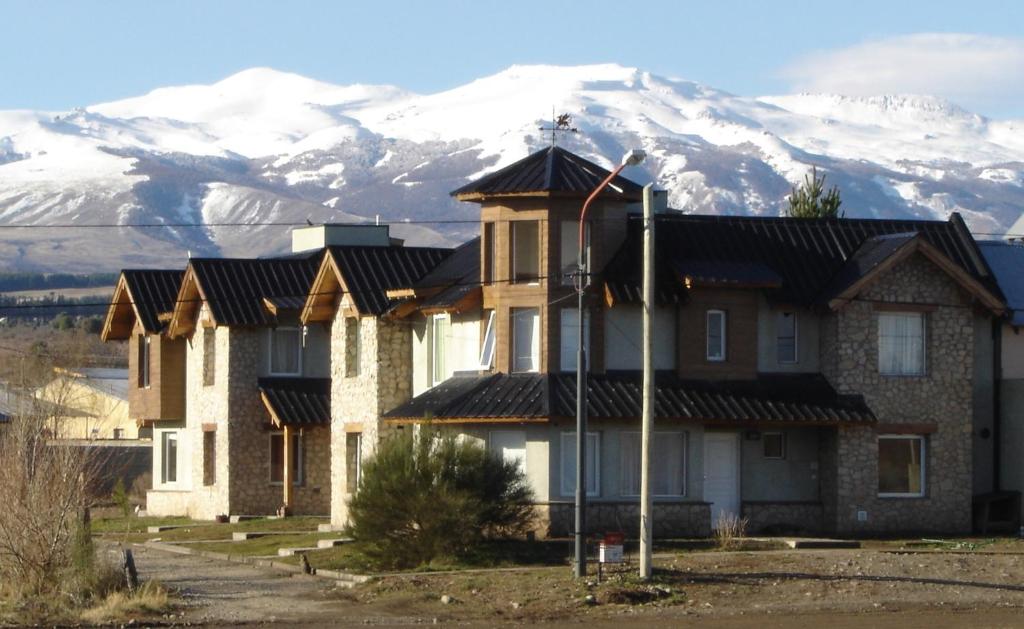 a house with snow covered mountains in the background at Valle del Molino in Trevelin